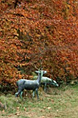BATSFORD ARBORETUM  GLOUCESTERSHIRE: A BRONZE STAG AND HIND BESIDE A BEECH TREE
