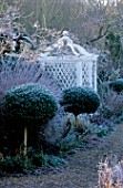 WEST GREEN HOUSE GARDEN  HAMPSHIRE: CLIPPED BOX LOLLIPOPS IN FRONT OF BORDER AND WHITE SEAT IN THE WALLED GARDEN IN WINTER IN FROST