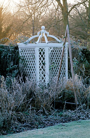 WEST_GREEN_HOUSE_GARDEN__HAMPSHIRE_FROSTY_BORDER_IN_WINTER_WITH_A_WOODEN_TRIPOD_IN_FRONT_OF_A_WHITE_