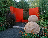 CHELSEA 2004: THE MERGER GARDEN DESIGNED BY ANDREW DUFF: SEMI CIRCULAR ORANGE RENDERED WALL AND WATER FEATURE WITH LARGE POPLAR SPHERES CUT FROM TREE STUMPS