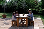 DESIGNER CLARE MATTHEWS: STONE TERRACE WITH TABLE AND CHAIRS AND FAMILY ENJOYING BREAKFAST