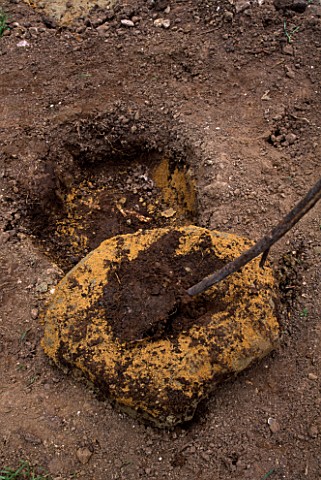 DESIGNER_CLARE_MATTHEWS_DINOSAUR_FOOTPRINTS_CLEANING_CEMENT_MOULD_WITH_A_STICK