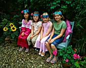 DESIGNER CLARE MATTHEWS: CHILDRENS PARTY -  FOUR GIRLS ON A BLUE BENCH WEARING SELF MADE PARTY HATS