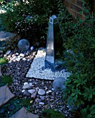 MIRRORED OBELISK WATERFEATURE SURROUNDED BY RECYCLED GLASS BOTTLES AND CIRCULAR PAVED AREA. DESIGNER: DAVID CHASE