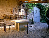 LA CHABAUDE  FRANCE. DESIGNER - PHILIPPE COTTET: A PLACE TO SIT: COBBLED TERRACE WITH TABLE AND CHAIRS