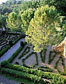 LA CHABAUDE  FRANCE. DESIGNER - PHILIPPE COTTET: VIEW OF GRAVEL AND BOX PARTERRE FROM TOP OF HOUSE WITH PINE TREES