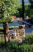 LA CHABAUDE  FRANCE. DESIGNER - PHILIPPE COTTET: STONE WALL WITH ROCK  GRAVEL TERRACE AND LONG WOODEN BENCH