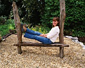 DESIGNER CLARE MATTHEWS SITS ON A HOME MADE WOODEN SEAT