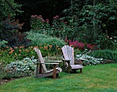 TWO ADIRONDACK CHAIRS IN FRONT OF A BORDER WITH LIATRIS  HEMEROCALLIS AND EUPATORIUM. DESIGNER: DUNCAN HEATHER   GREYSTONE COTTAGE  OXFORDSHIRE