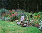SWEEPING BORDER BESIDE WOODEN ADIRONDACK CHAIRS WITH ECHINACEA  NEPETA AND GRASSES. DESIGNER: DUNCAN HEATHER  GREYSTONE COTTAGE  OXFORDSHIRE