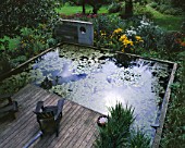 CONCRETE SCULPTURE  LILY POND  DECKING AND ADIRONDACK CHAIRS. DESIGNER: DUNCAN HEATHER  GREYSTONE COTTAGE  OXFORDSHIRE