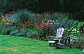 LAWN  WOODEN ADIRONDACK SEATS AND BORDER PLANTED WITH NEPETA  ECHINACEAS AND GRASSES. DESIGNER: DUNCAN HEATHER  GREYSTONE COTTAGE  OXFORDSHIRE
