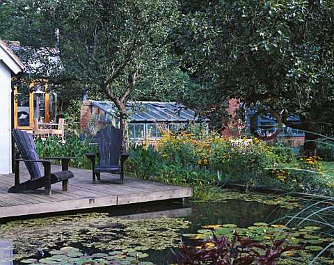 VIEW_ACROSS_LILY_POOL_TO_DECK_WITH_ADIRONDACK_CHAIRS_IN_THE_BACKGROUND_IS_THE_MAIN_GREENHOUSE_GREYST