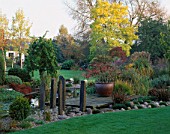VIEW TOWARDS THE HOUSE WITH THE LILY POOL  WOODEN PONTOON AND STONE SCULPTURES. DESIGNER: JOHN MASSEY