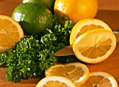 SLICING LEMONS WITH LIMES AND PARSLEY IN BACKGROUND
