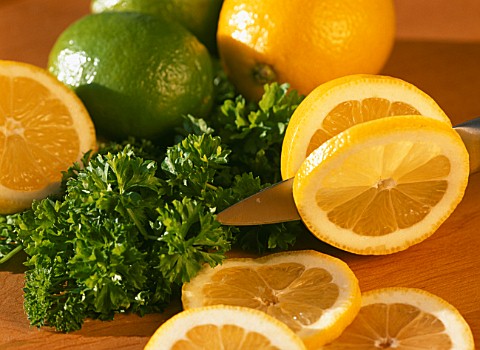 SLICING_LEMONS_WITH_LIMES_AND_PARSLEY_IN_BACKGROUND