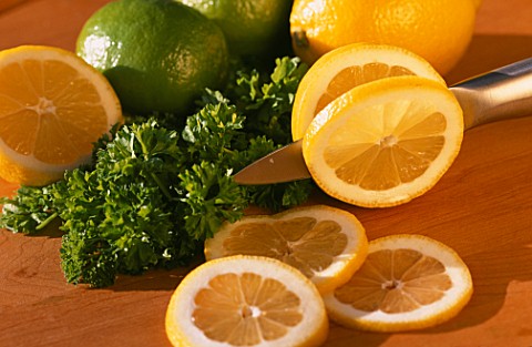 SLICING_LEMONS_WITH_PARSLEY_AND_LIMES_IN_BACKGROUND