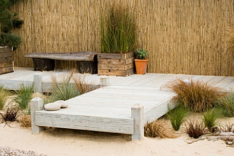 WOODEN_CONTAINERS_ON_DECKING_IN_SEASIDE_GARDEN_PLANTED_WITH_PINES_AND_GRASSES_DESIGNERS_NIGEL_DUFF_A