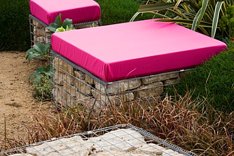 PINK_CUSHION_TOPPED_GABION_SEATS_IN_A_GARDEN_DESIGNED_BY_NIC_HOWARD_AND_BARNEY_HARRISON_THE_GREAT_GA