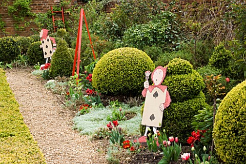 WEST_GREEN_HOUSE__HAMPSHIRE__SPRING_ALICE_IN_WONDERLAND_CHARACTERS_BESIDE_BORDER_WITH_CLIPPED_TOPIAR