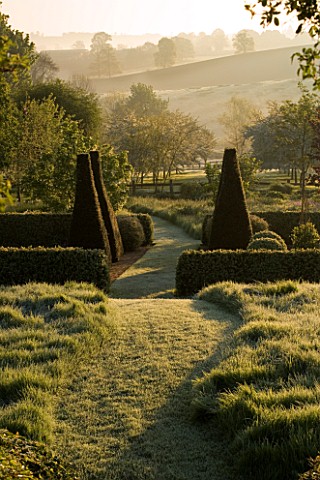 PETTIFERS_GARDEN__OXFORDSHIRE_EARLY_MORNING_MIST_IN_SPRING_OVER_THE_LOWER_PARTERRE_WITH_THE_COUNTRYS