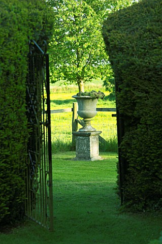 VIEW_THROUGH_YEW_HEDGES_TO_STONE_URN_ON_PEDESTAL_JANET_CROPLEY_GARDEN__HILL_GROUNDS__NORTHAMPTONSHIR