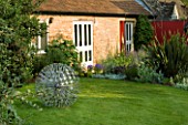 THE LAWN AT THE BACK OF THE GARDEN WITH ALLIUM  A SCULPTURE BY RUTH MOILLIET. WINGWELL NURSERY   RUTLAND
