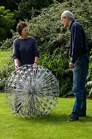 ROSE_AND_JOHN_DEJARDIN_ON_THE_LAWN_WITH_ALLIUM__A_SCULPTURE_BY_RUTH_MOILLIET_WINGWELL_NURSERY___RUTL