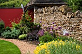 A BORDER BESIDE A STONE WALL PLANTED WITH ALLIUMS AND HELIANTHEMUM FEATURES A DELICATE GLASS SCULPTURE BY NEIL WILKIN. WINGWELL NURSERY   RUTLAND