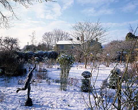 WINTER__WOODCHIPPINGS__NORTHAMPTONSHIRE_THE_GARDEN_IN_SNOW_WITH_A_STATUE_IN_THE_FOREGROUND_AND_THE_H