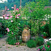 METAL ARBOUR WITH CLIMBING ROSE HANDEL SURROUNDS AN OLD EGYPTIAN VASE PLANTED WITH SEMPERVIVUM. LOWER HALL GARDEN  SHROPS.