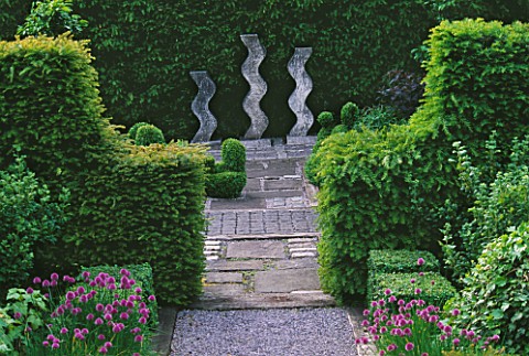 RIDLERS_GARDEN__SWANSEA__WALES_VIEW_ALONG_PATH_WITH_CHIVES_AND_YEW_HEDGE_TO_SCULPTURE_BY_HELEN_SINCL