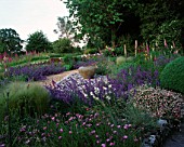 CLARE MATTHEWS GARDEN  DEVON: THE GRAVEL GARDEN WITH ERIGERON  NEPETA WALKERS LOW  FOXGLOVES  SLATE  LARGE EMPTY URN (CONTAINER)  AND RUSTIC WOODEN BENCH