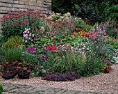 MAYROYD MILL HOUSE  YORKSHIRE: DESIGNERS: RICHARD EASTON AND STEVE MACKAY. COLOURFUL HERBACEOUS PERENNIAL BORDER IN GRAVEL NEXT TO PATH