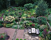 MAYROYD MILL HOUSE  YORKSHIRE: DESIGNERS: RICHARD EASTON AND STEVE MACKAY. VIEW ONTO COLOURFUL OF HERBACEOUS PERENNIAL BORDERS AND SEATING AREA IN WITH TABLE AND CHAIRS IN GRAVEL
