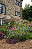 MAYROYD MILL HOUSE  YORKSHIRE. DESIGNERS RICHARD EASTON AND STEVE MACKAY. BORDER BESIDE THE MILL WITH HELENIUMS  SEDUMS AND EUPATORIUM