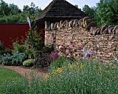 WINGWELL NURSERY  RUTLAND: STONE WALL WITH BORDER OF ALLIUMS AND STACHYS. GLASS SCULPTURE BY NEIL WILKIN  BIRD MAN SCULPTURE BY CHRIS MARVELL