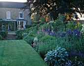 HALL FARM  LINCOLNSHIRE: VIEW ALONG DOUBLE HERBACEOUS BORDERS TO THE HOUSE IN THE MORNING