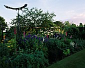 HALL FARM  LINCOLNSHIRE: VIEW ALONG HERBACEOUS BORDER WITH SCULPTURE OF EAGLE BY PAUL GILBARD