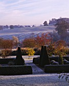 VIEW ACROSS PARTERRE TO OPEN COUNTRYSIDE WITH RIDGE AND FURROW FIELD  AT PETTIFERS IN  FROST.  TOPIARY