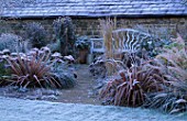 PETTIFERS  OXFORDSHIRE: FROSTY BORDER WITH BLUE WOODEN BENCH  PHORMIUMS AND SEDUMS