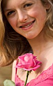 GIRL (AGED 13) SMILING AT A PINK ROSE  WEARING A PINK DRESS