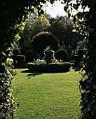 CHENIES MANOR GARDEN  BUCKINGHAMSHIRE: VIEW INTO THE WHITE GARDEN IN SPRING WITH BOX AND YEW TOPIARY AND WHITE TULIPS