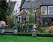 LISETTE PLEASANCE GARDEN  LONDON: VIEW TO DECKED TERRACE AND CONSERVATORY WITH LEAD TABLE  CHAIRS  AND METAL CONTAINERS PLANTED WITH TULIP BALLERINA
