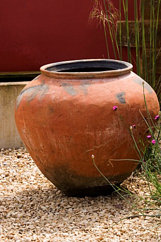 RICKYARD_BARN__NORTHAMPTONSHIRE_THE_GRAVEL_COURTYARD_IN_JUNE_WITH_LARGE_TERRACOTTA_CONTAINER_AND_RED