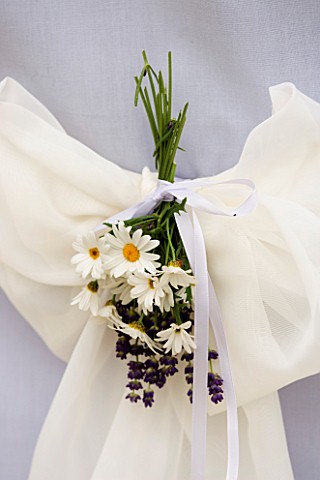 DESIGNER_CLARE_MATTHEWS_CHAIR_COVERED_WITH_PALE_BLUE_SHEET_WITH_WHITE_RIBBON_AND_BOUQUET_OF_LAVENDER