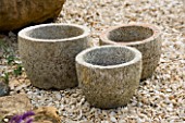 RICKYARD BARN GARDEN  NORTHAMPTONSHIRE: STONE CONTAINERS FROM INDIA IN GRAVEL GARDEN