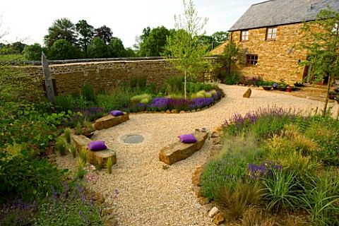RICKYARD_BARN_GARDEN__NORTHAMPTONSHIRE_VIEW_OVER_THE_GRAVEL_GARDEN_WITH_ROCK_SEATS__CUSHIONS__THE_HO