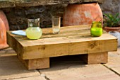 DESIGNER: CLARE MATTHEWS - LOW SLEEPER TABLE PROJECT: LOW SLEEPER TABLE ON PATIO WITH YELLOW CANDLE AND ORANGE JUICE