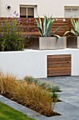 MINIMALIST GARDEN BY WYNNIATT-HUSEY CLARKE: STIPA TENUISSIMA IN GREY SLATE PATIO WITH METAL CONTAINER PLANTED WITH AGAVE BEHIND